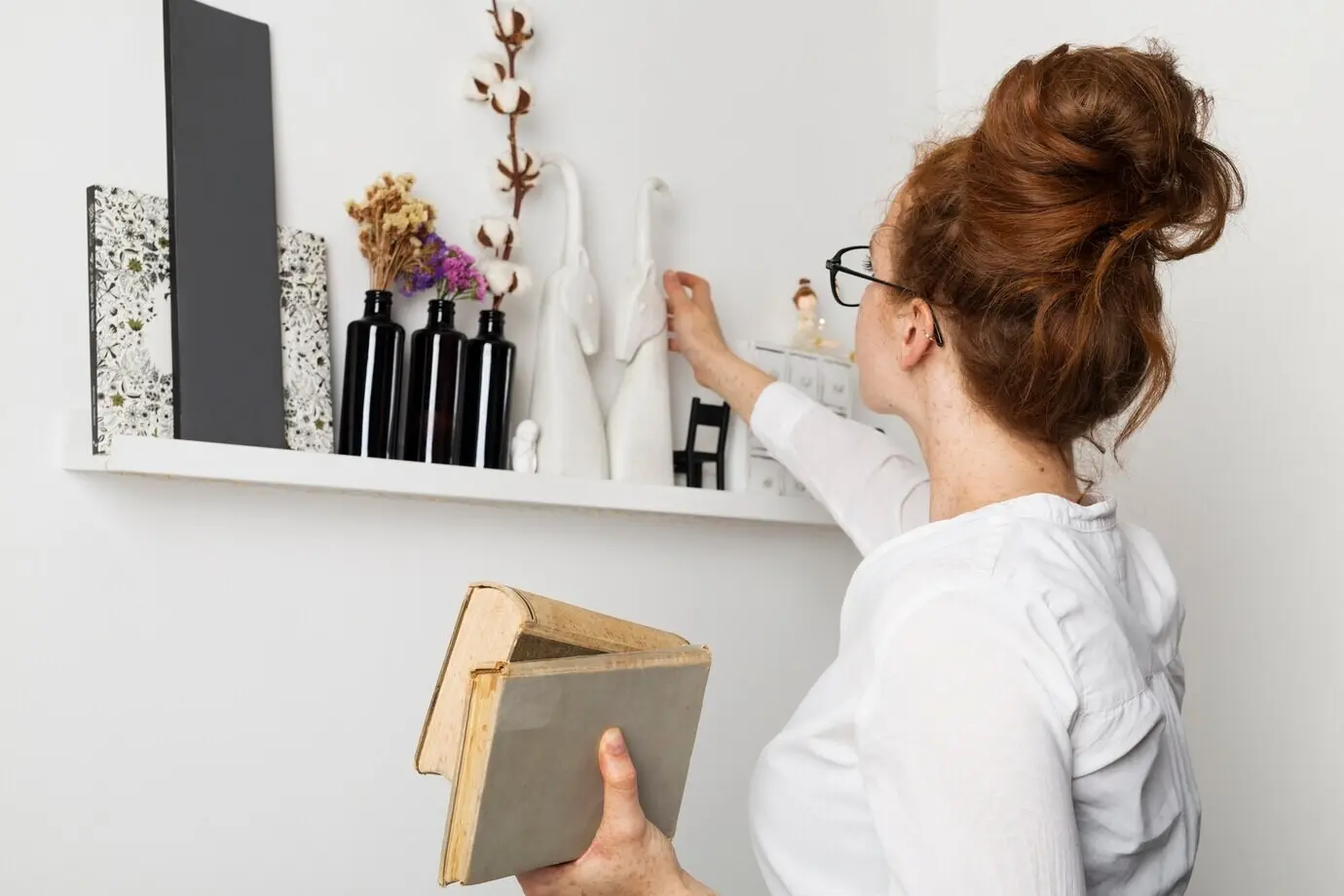 Front-facing view of a woman at home taking books from a shelf.
